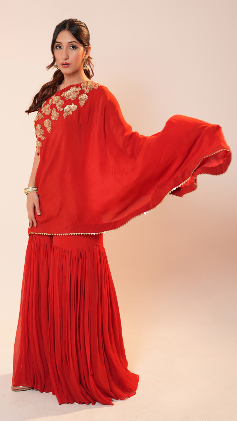Woman wearing a red traditional outfit with gold embroidery on a beige background