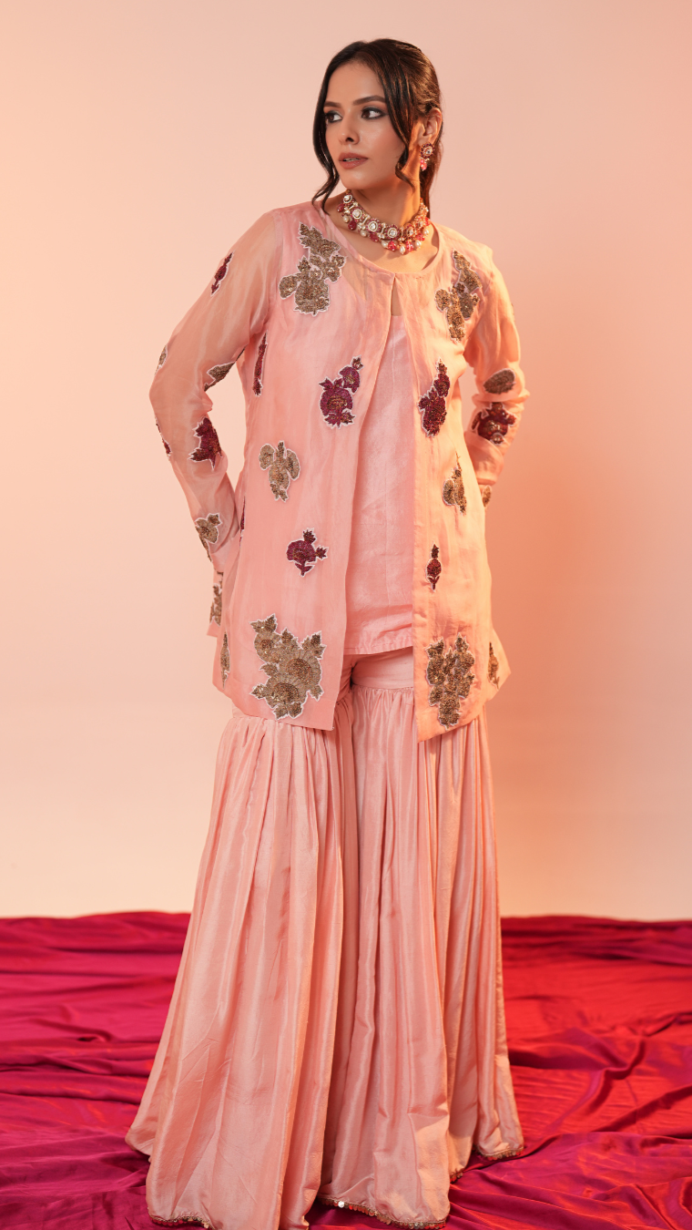 Woman wearing a pink traditional outfit with floral patterns on a red and pink gradient background