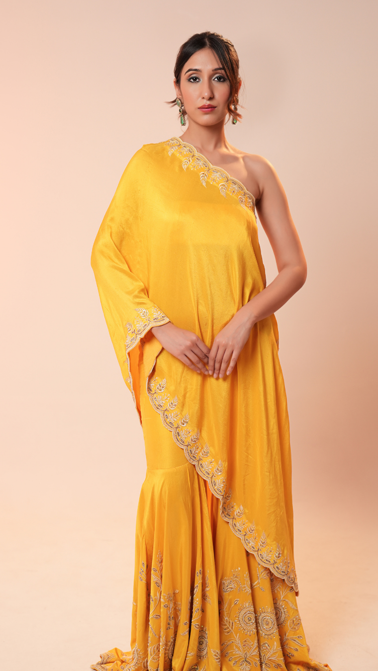 Woman wearing a yellow saree with intricate designs on a beige background