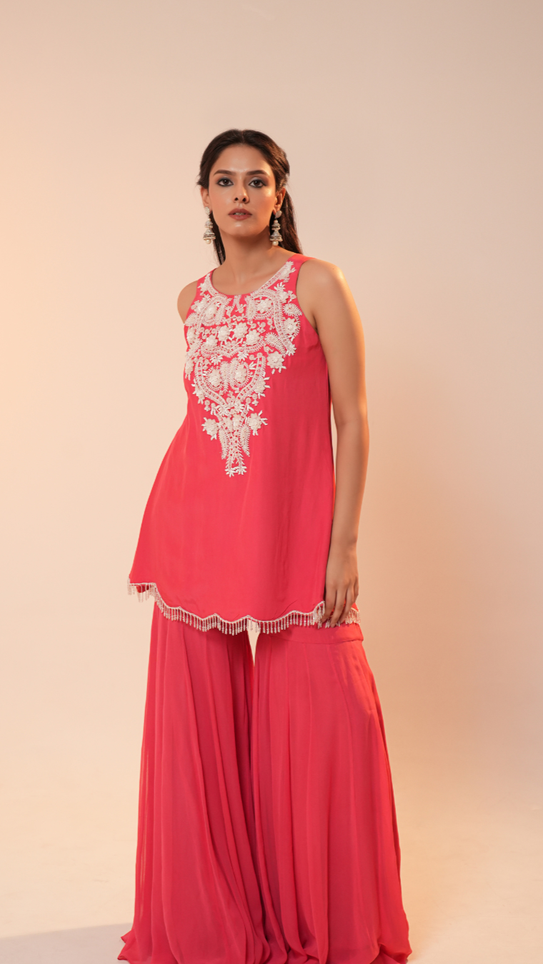 Woman wearing a coral pink dress with white lace details on a beige background