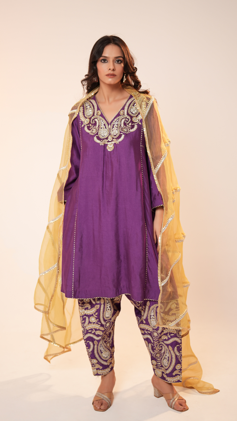 Woman wearing a purple outfit with yellow dupatta on a white background