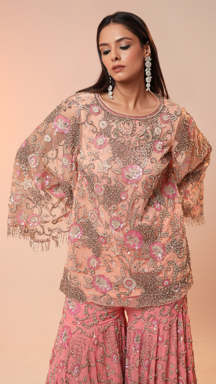Woman wearing a pink floral outfit with a soft peach background