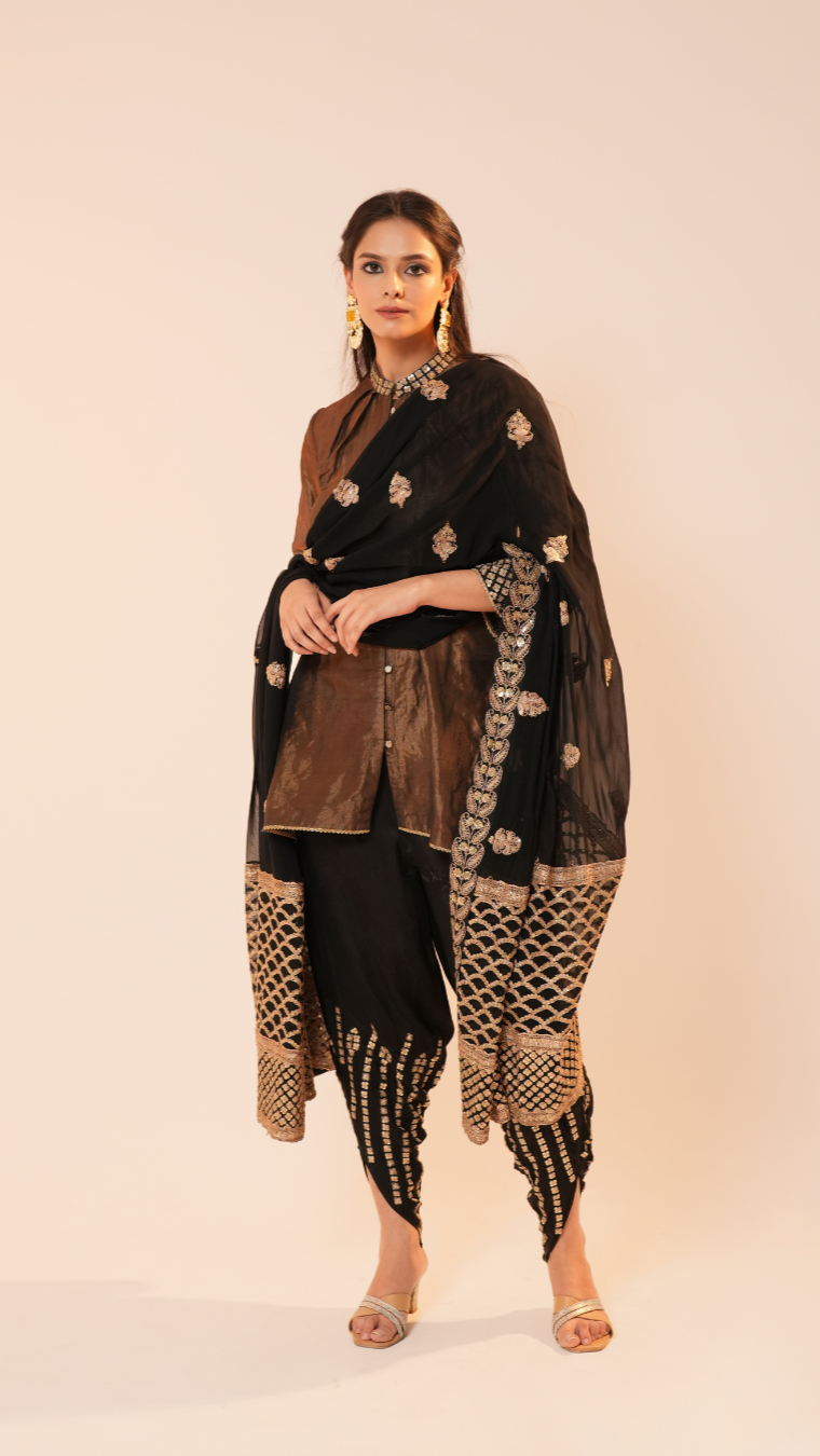 Woman wearing a traditional outfit with a black dupatta and gold patterns on a beige background