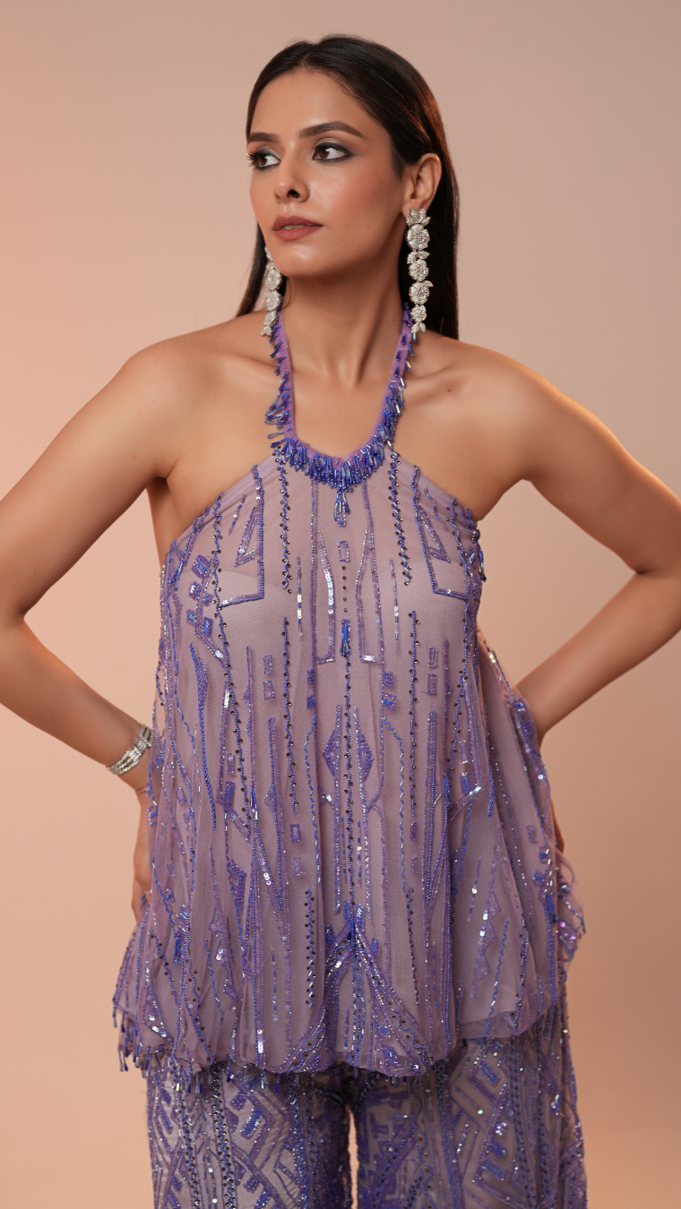 Woman wearing a purple beaded outfit with a plain background