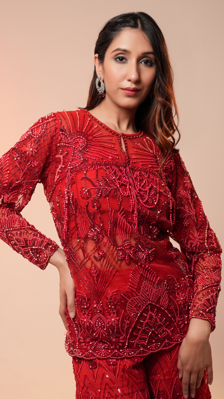 Woman wearing a red embroidered outfit against a beige background