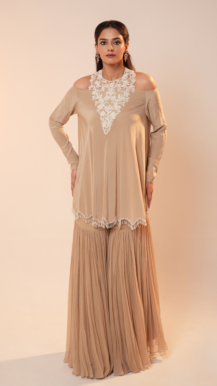 Woman wearing a beige outfit with lace details on a beige background