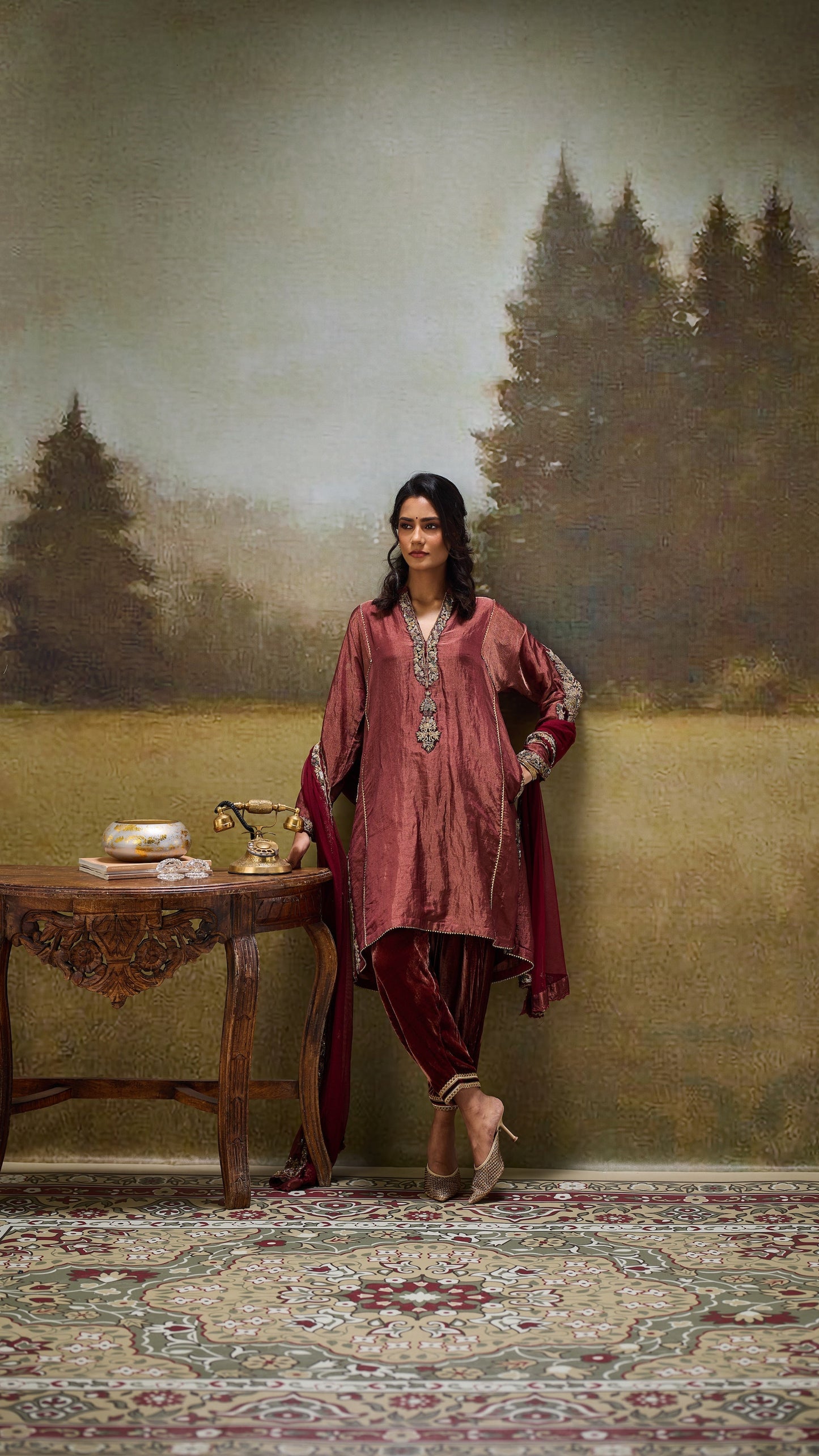 Woman in traditional attire standing in a room with a table and decorative elements.