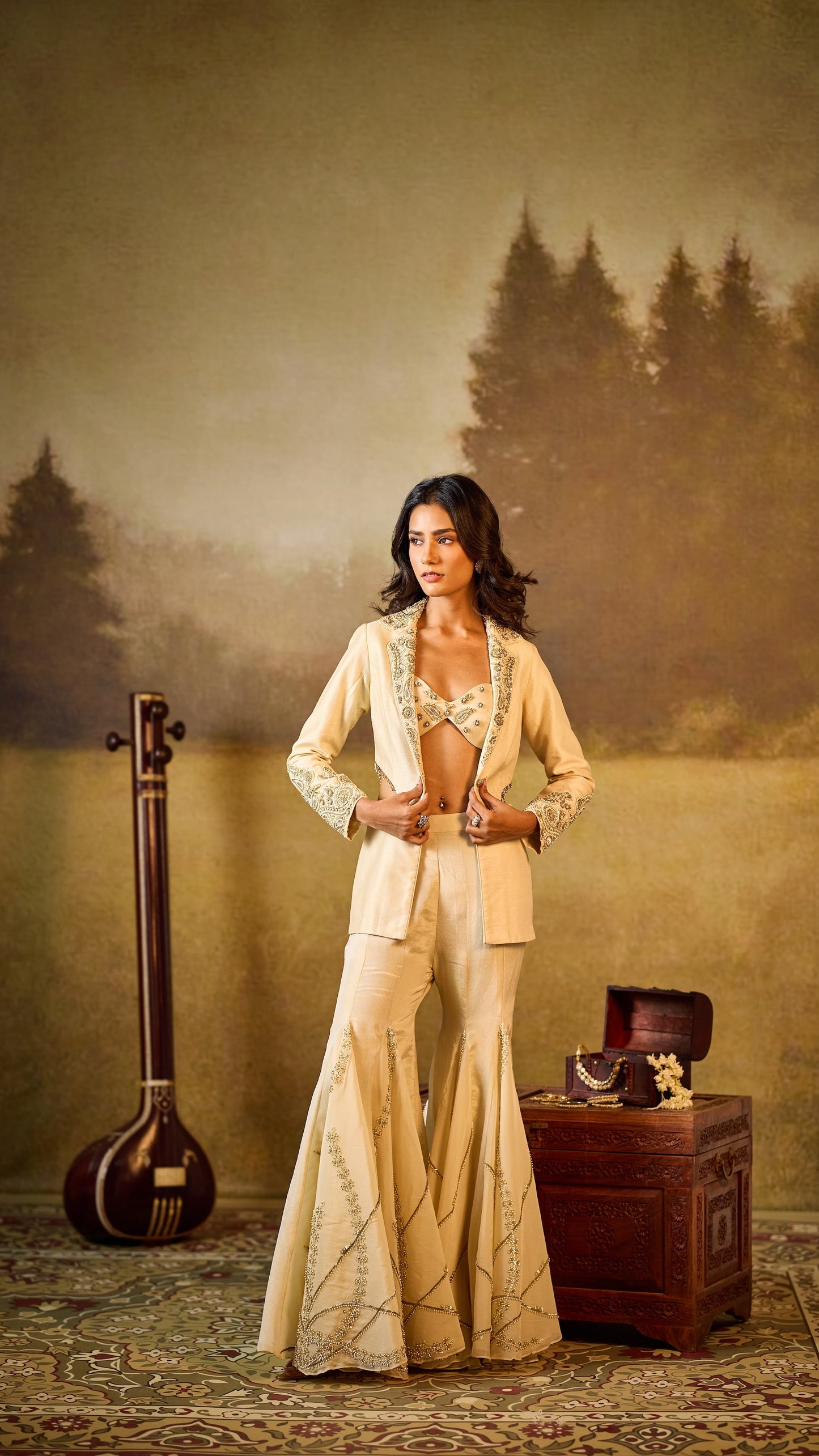 Woman in a beige suit standing in a misty forest with a musical instrument and wooden chest.
