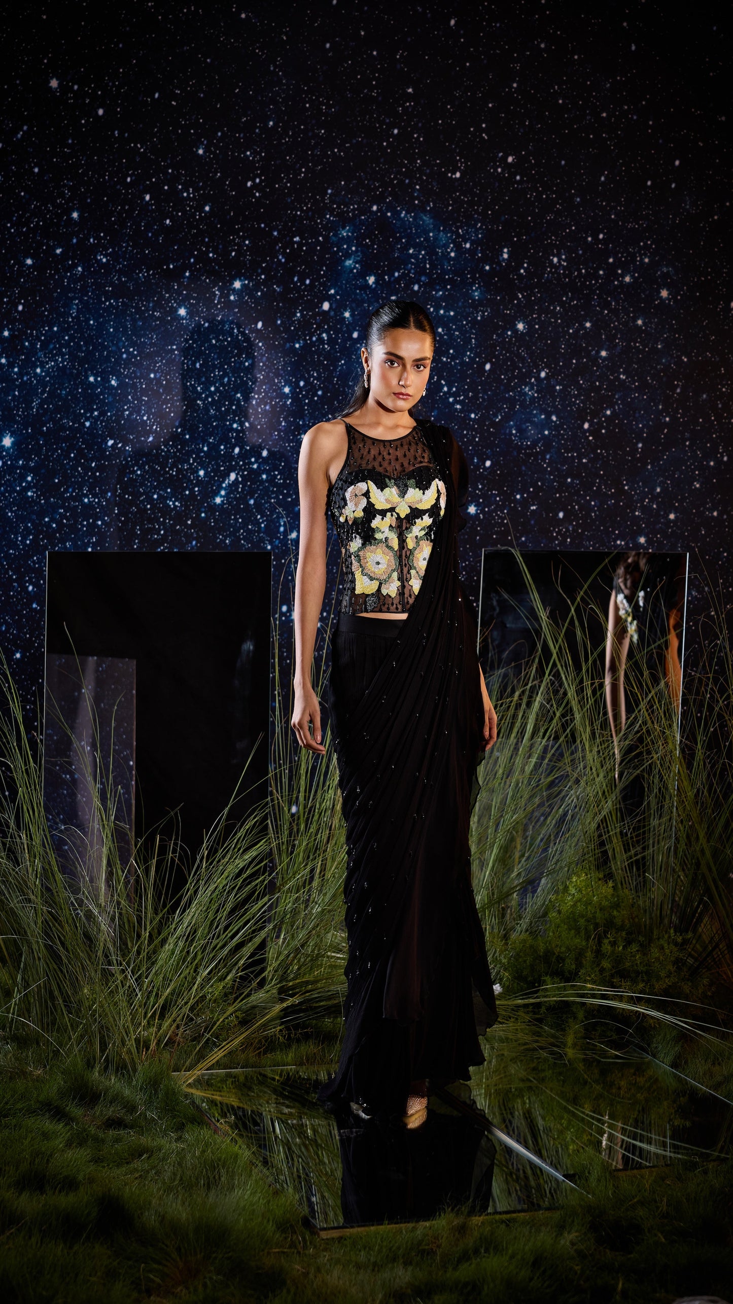 Woman in a black outfit with a graphic design standing in front of a starry night sky.