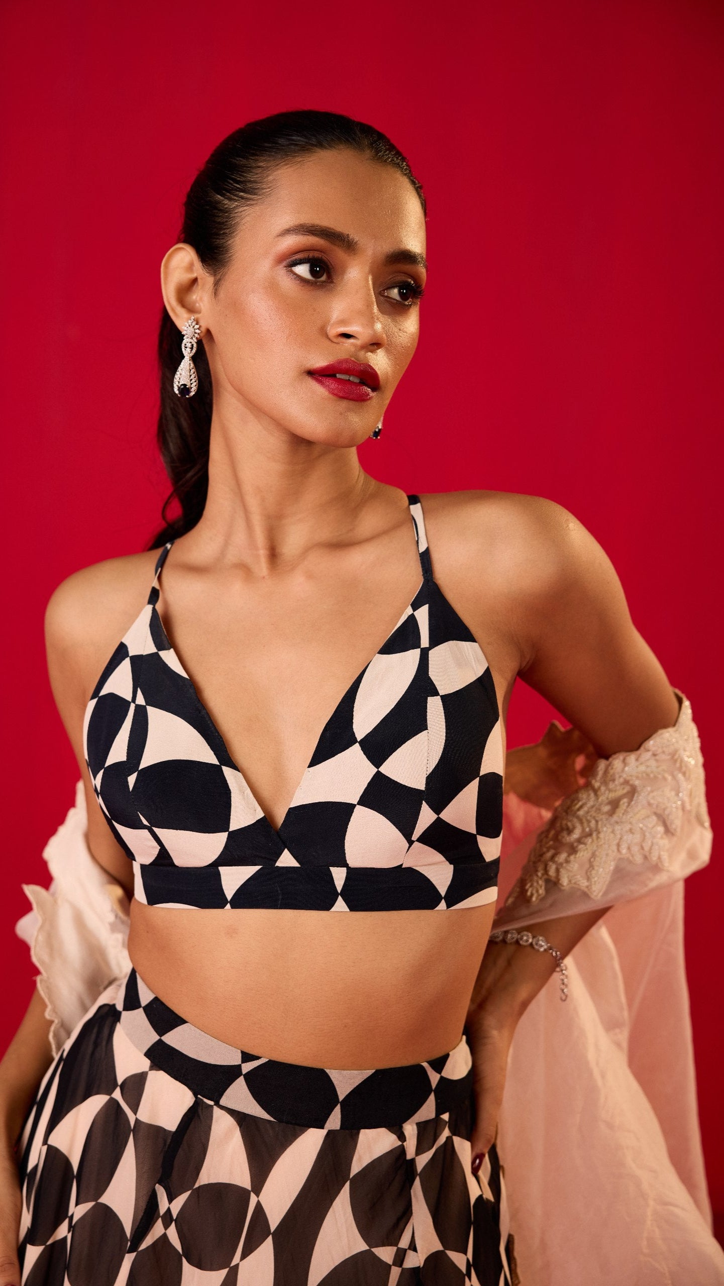 A woman wearing a black and white geometric patterned crop top and skirt.