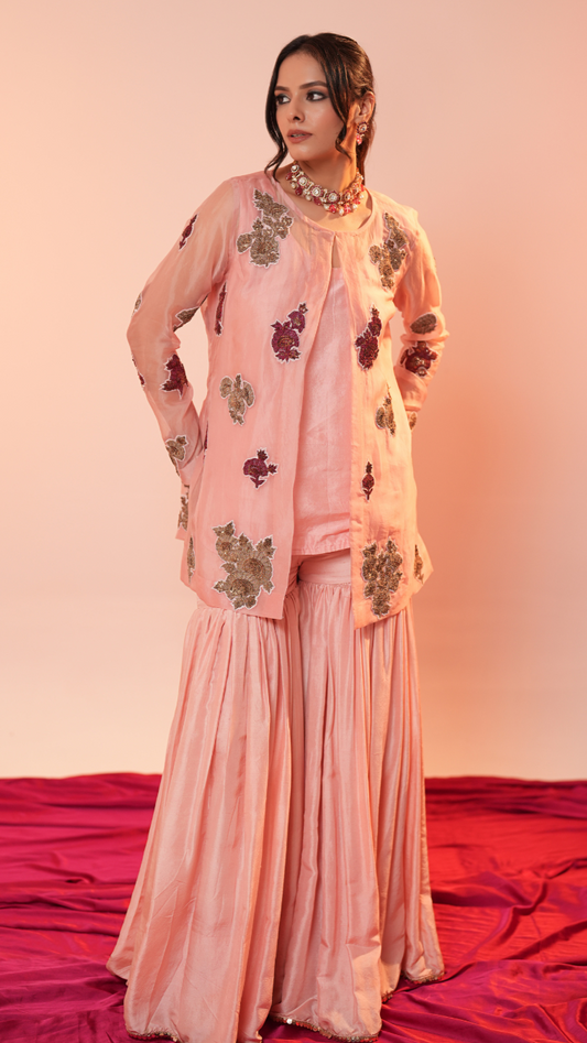 Woman wearing a pink traditional outfit with floral patterns on a red and pink gradient background
