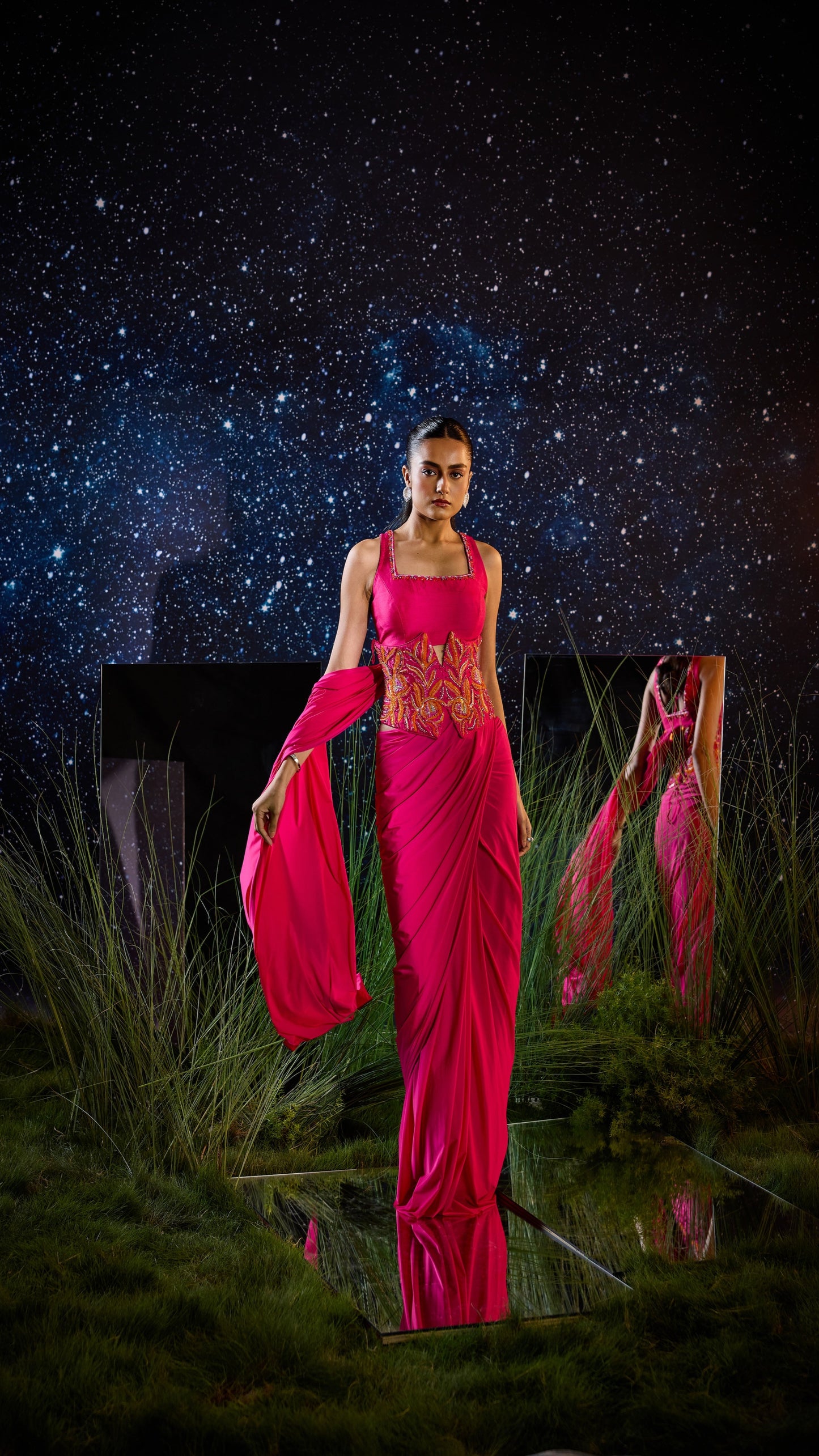 Woman in a bright pink saree with a starry night sky background