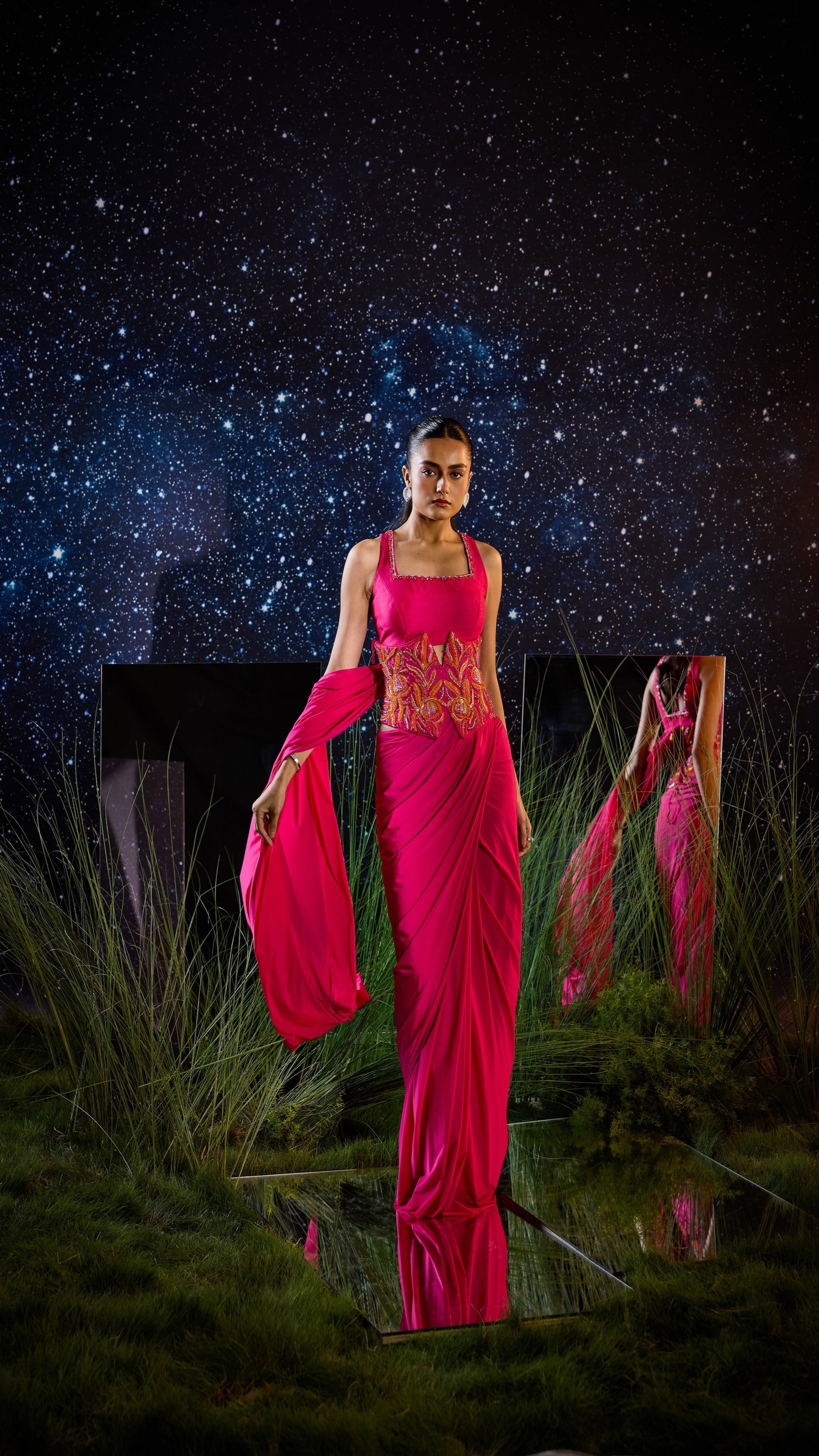 Woman in a bright pink saree with a starry night sky background
