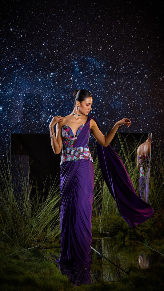 Woman in a purple saree with a starry night sky and grass in the foreground