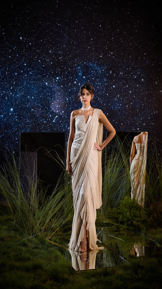 Woman in a saree standing in a grassy area with a starry night sky.