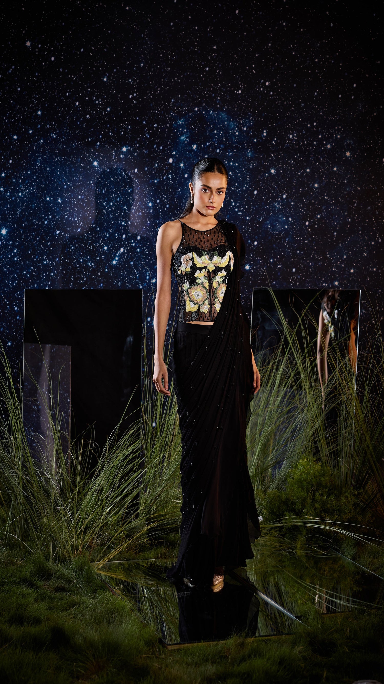Woman in a black outfit with a graphic design standing in front of a starry night sky.